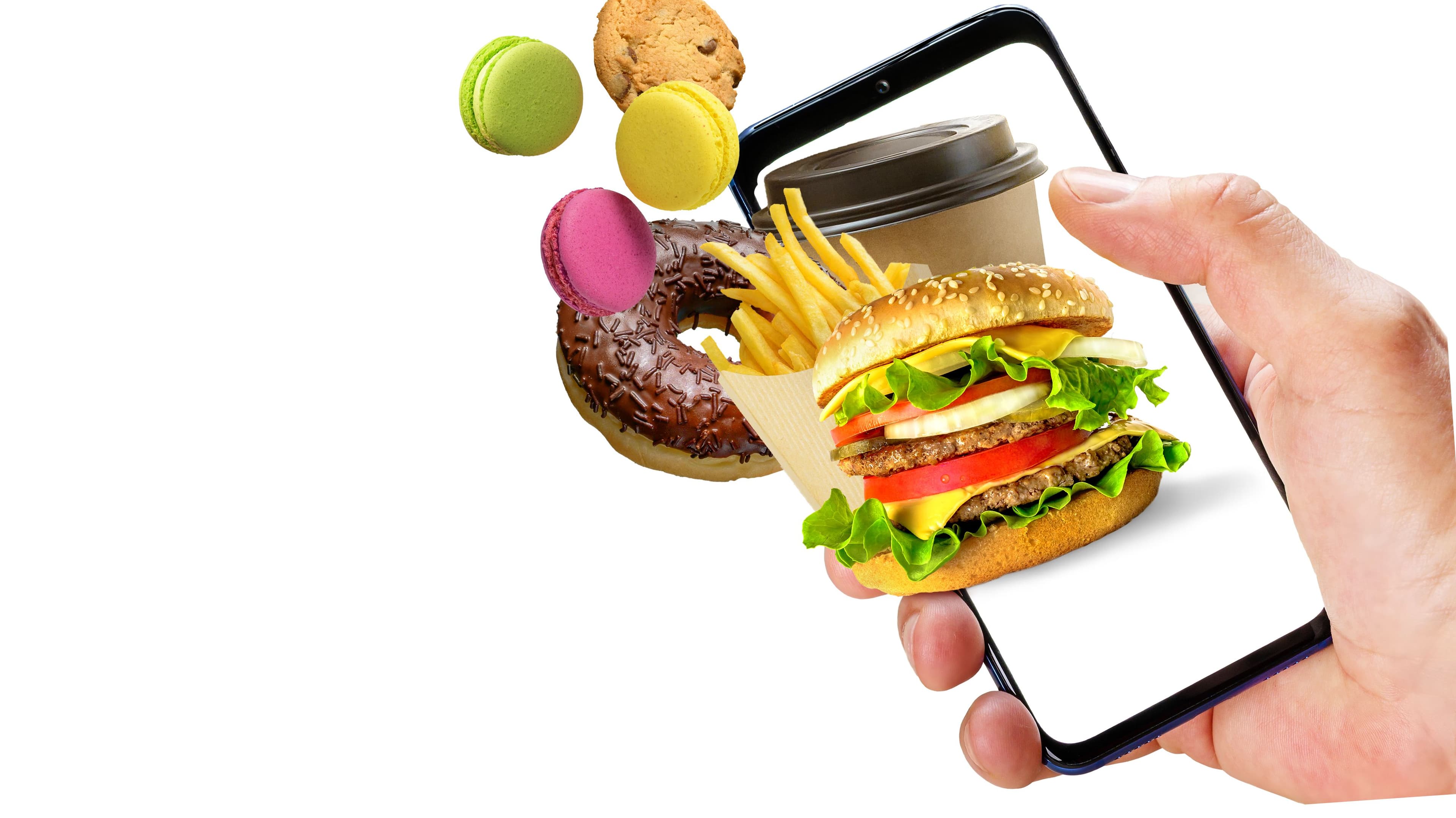 photologuephotos2025-07mano-sujetando-el-telefono-con-hamburguesa-papas-fritas-taza-de-cafe-donuts-volando-fuera-de-la-pantalla-aislada-sobre-fondo-blanco-pedidos-en-linea-de-comida-rapidajpg