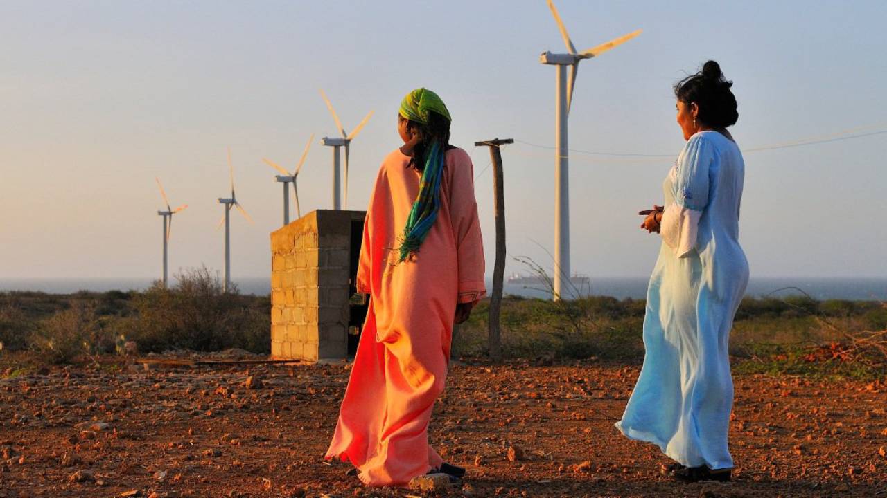 Mujeres wayuu observan los aerogeneradores instalados en La Guajira, epicentro de los proyectos eólicos que avanzan en el norte del país. Foto: Ministerio de Minas y Energía