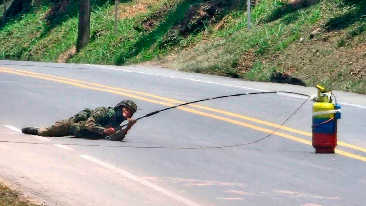 El soldado Maldonado, experto antiexplosivos, desactivando  con un sistema artesanal &mdash;semejante a una ca&ntilde;a de pescar&mdash;, un cilindro bomba en la carretera Panamericana en Santander de Quilichao, a finales de 2025. Foto: captura de video de las Fuerzas Armadas.